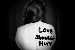 A woman with the phrase 'love shouldn't hurt' painted on her back.