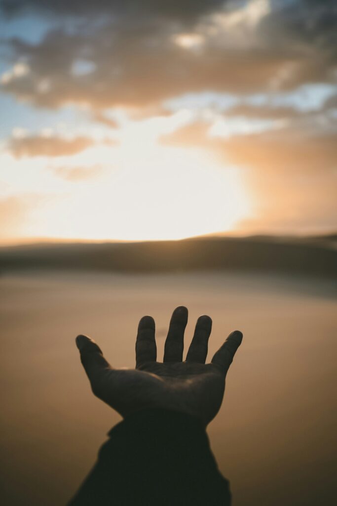 A hand stretches out, palm facing up, reaching for the Sun.