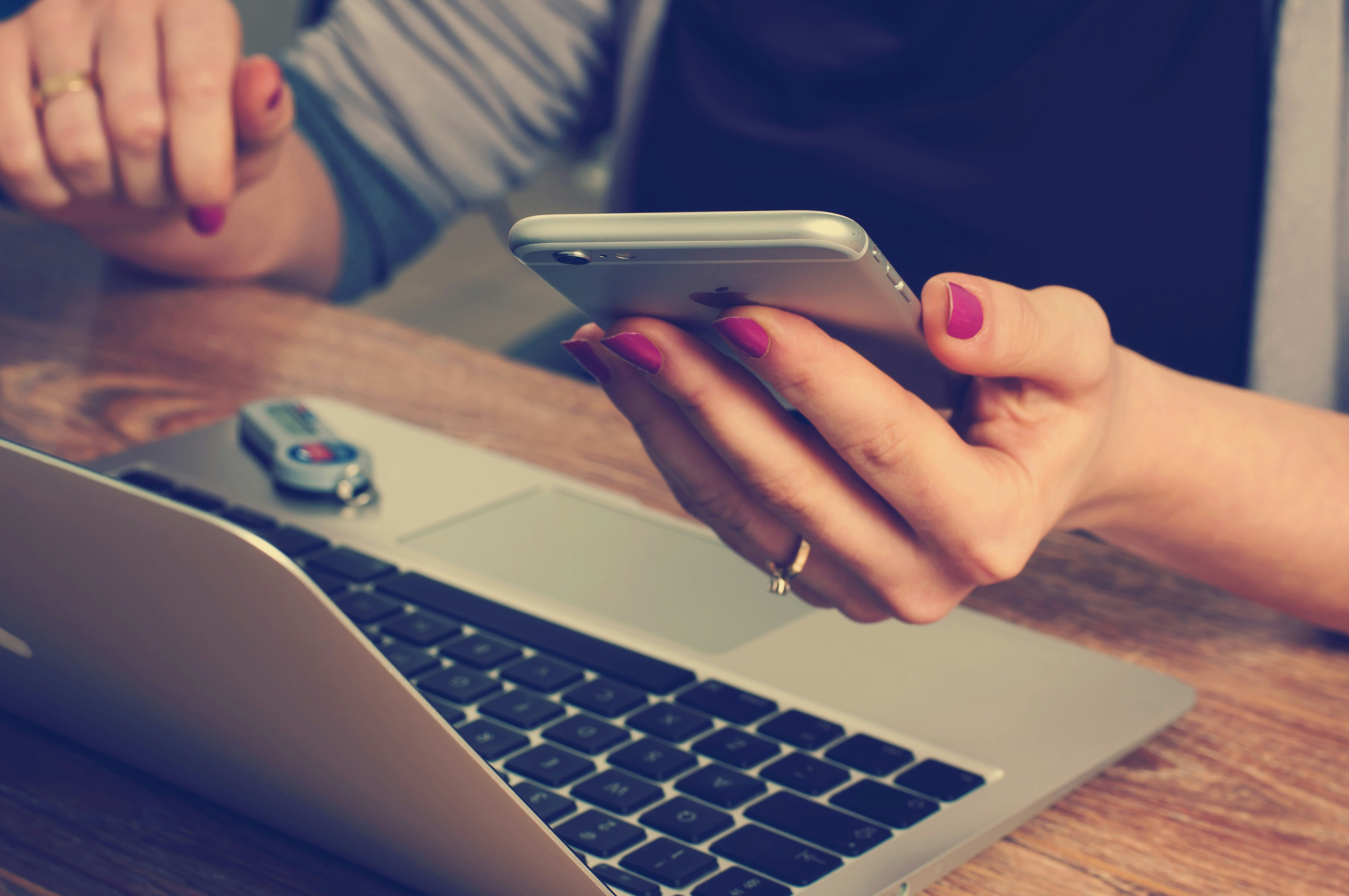 A woman using both her cell phone and a laptop at the same time.