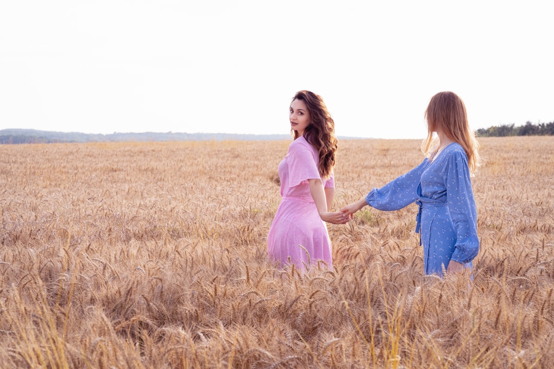 two women in a wheat field holding hands